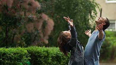 Outdoors portrait of two beautiful lovers enjoying warm summer rain. Brunette woman and her boyfriend in wet clothing