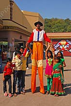 Friendly Clown on Stilts smiling widely while posing with Children at Ramoji Film City - world`s largest film studio complex