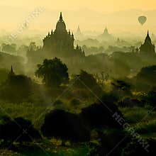 Scenic sunrise with silhouette balloons above ruin pagoda in Bagan, Myanmar.