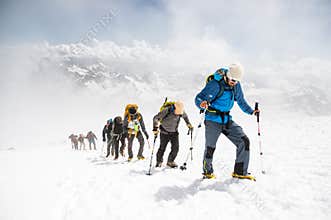 A group of mountaineers climbs to the top of a snow-capped mountain