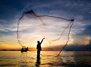 Silhouette of fisherman casting fishing net into the sea
