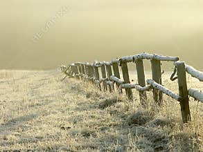 Idyllic fence on a misty field at sunrise