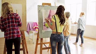 Students with easels painting at art school