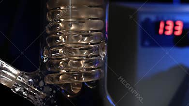 Crystal Spiral. Spiral glass tube with water close up. Glass spiral pipe from the reflux condenser with running water