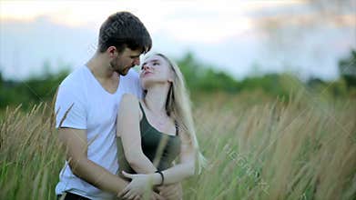 Romantic Couple at Sunset. Two people in love at sunset or sunrise. Man and woman kissing on field