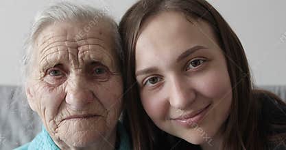 Grandmother and granddaughter faces looking together at camera.