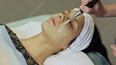 Spa therapy for young woman having cosmetic mask at beauty salon. Applying a chocolate mask to the girl`s face.
