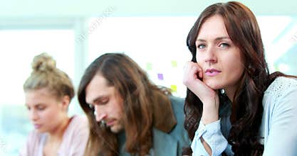 Daydreaming casual businesswoman between colleagues
