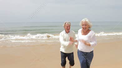 Senior Couple Running On Fall Beach