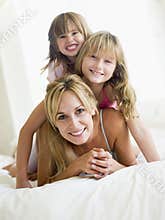 Woman and two young girls in bed playing