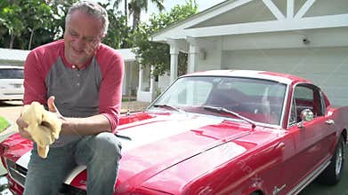 Retired Senior Man Sitting On Hood Of Restored Classic Car