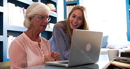 Daughter Helping Senior Mother With Computer In Home Office