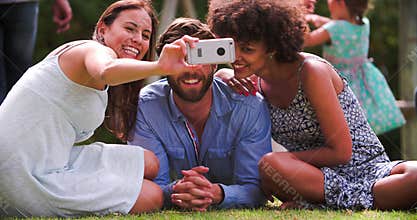 Group Of Friends In Garden Taking Selfie On Mobile Phone
