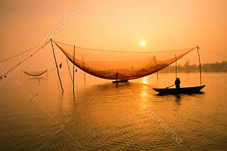 Unidentified fisherman checks his nets in early morning on river in Hoian, Vietnam