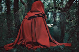 Mysterious hooded woman in front of a magical mirror