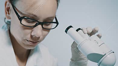 Young doctor looking through the microscope