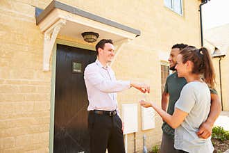 Real estate agent giving house keys to new property owners