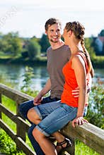 Couple sitting at riverbank in summer