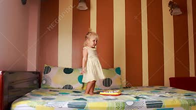 little blonde girl dances with joy around new toy on sofa