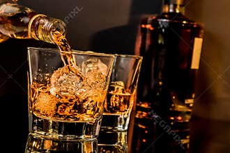 Barman pouring whiskey in front of whiskey glass and bottles