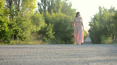 Girl in a pink dress walking on the road