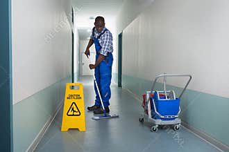 Male Janitor Mopping In Corridor