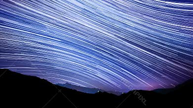 Star trail effect over mountain night sky.