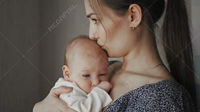 Young Mother Holding her Newborn Sleeping Child. Family at home