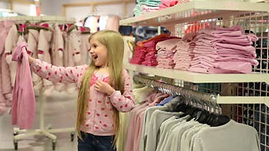 Baby girl looking at clothes in fashionable shop