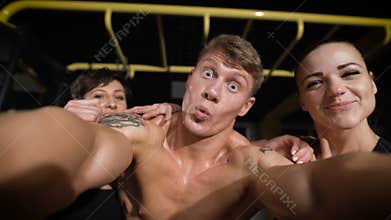 Two girl and one man making selfie photo in gym