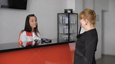 Pretty senior lady checking in at the doctor's office reception desk.