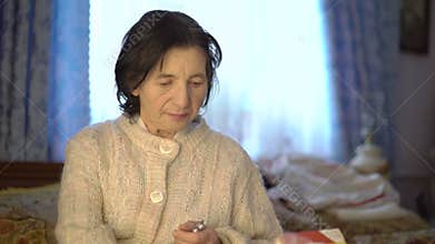 Retired elderly Ukrainian woman using medicine and reading