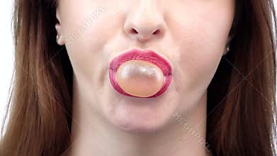 Female is blowing a big bubble with her gum. Closeup