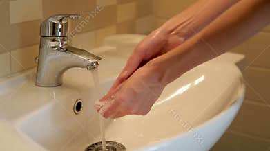 Girl washes her hands under the tap