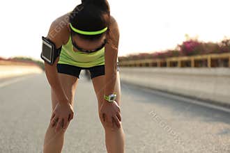 Tired woman runner taking a rest after running hard