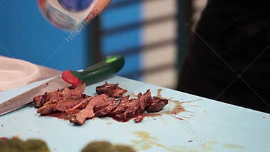 Chef cutting the meat into pieces and put on the plate