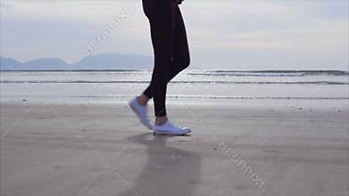 Low section slow motion of woman walking on wet shore