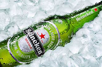 Frosty Heineken beer bottle laying on ice cubes 