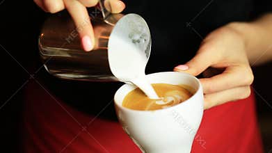 Hands of barista making latte or cappuccino coffee pouring milk making latte art.