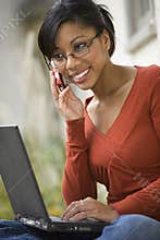 Black woman outside on cell phone and laptop