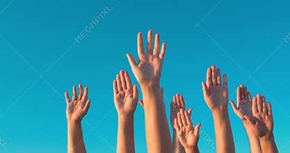 Raised hands against blue sky