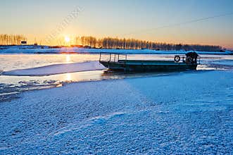The frozen river and boat sunset