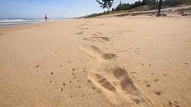 Camera Moves along Footprints Left on Wet Sand