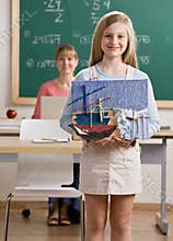 Student holding art project in school classroom