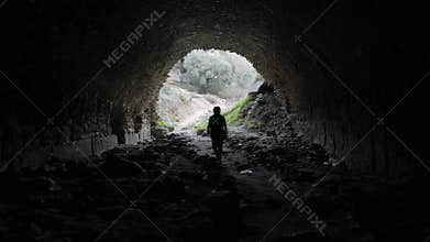 Woman walking out from the ancient underpass in Nysa, Sultanhisar, Turkey. Light at the end of tunnel. 4k.