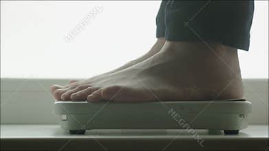 Man Weighing Himself with Bathroom Scales