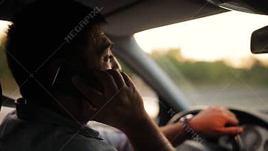 Handsome young man talking on mobile phone while driving his car . Risky, reckless driver bad habits. Traffic safety