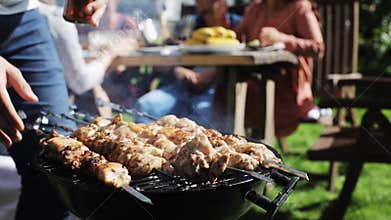 Man cooking meat on barbecue grill at summer party