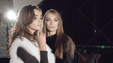 Two models stands in pose in fur coats in fashionable rich boutique