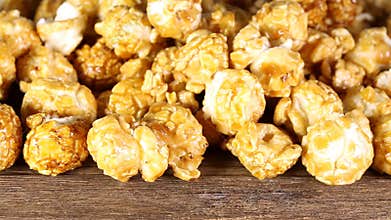 Sweet caramel popcorn on wooden background.
